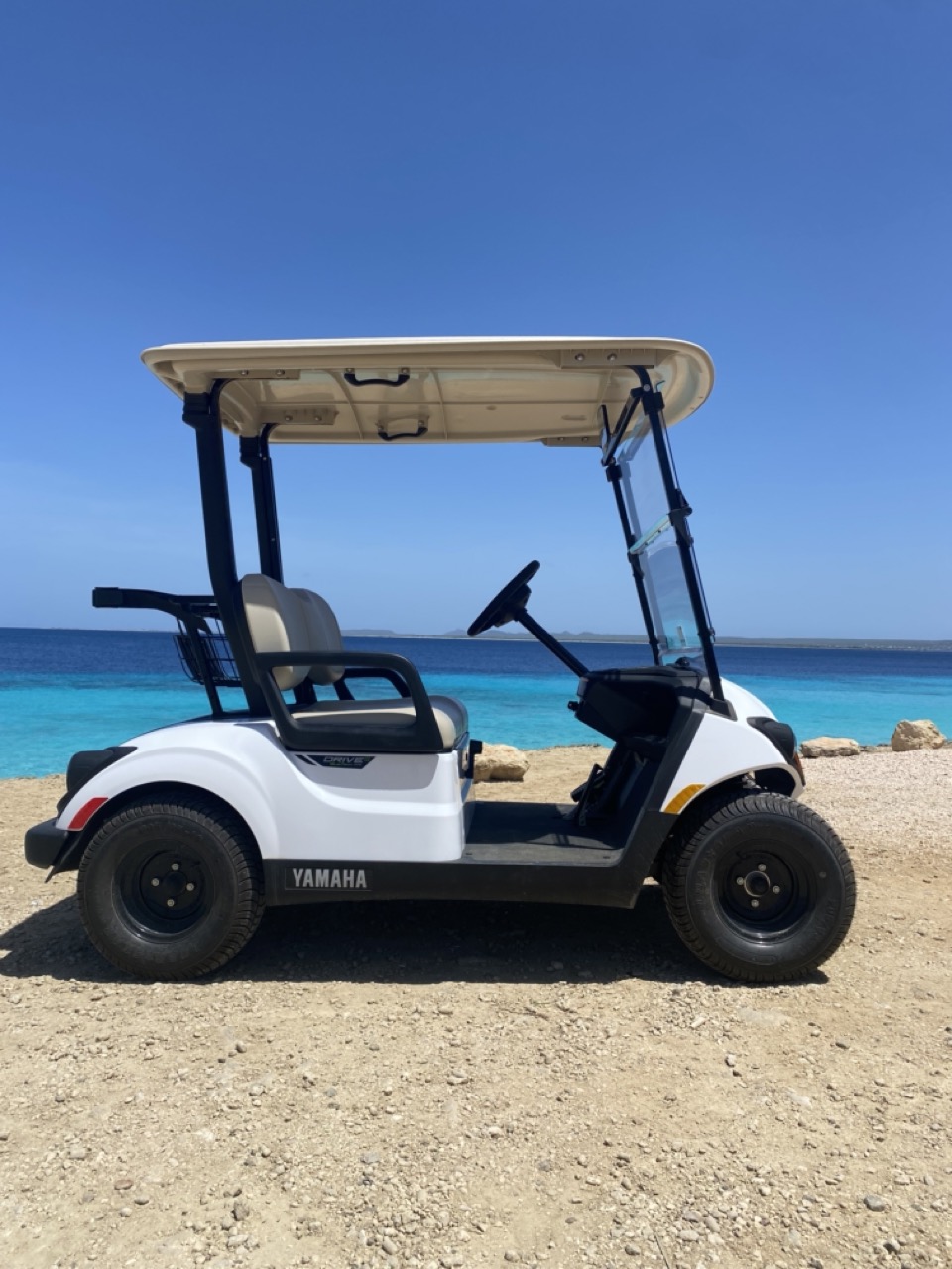 Zijaanzicht van een tweezits golfkar op Bonaire, ideaal voor een rondje eiland.